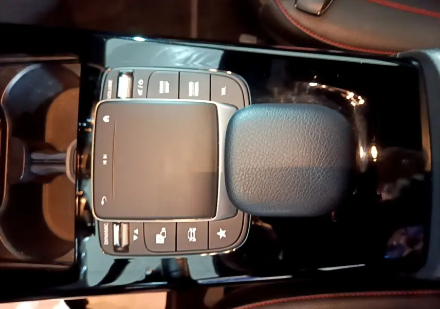 Gros plan sur la console centrale noire de la Mercedes Classe A 200 AMG Line, avec pavé tactile et accoudoir cuir.