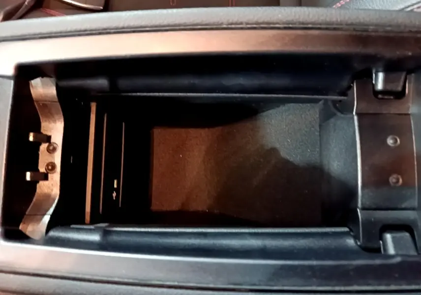 Vue plongeante sur le rangement central noir ouvert de la Mercedes Classe A 200 AMG Line 2021 avec clé visible.