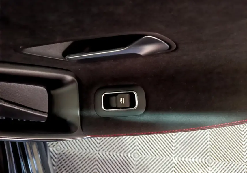 Détail intérieur de la porte côté conducteur de Mercedes Classe A 200 AMG Line noire, avec bouton ouverture coffre et surpiqûres rouges.
