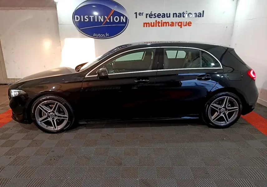 Vue de profil côté gauche d'une Mercedes Classe A 200 AMG Line noire, avec jantes alliage et feux arrière allumés.