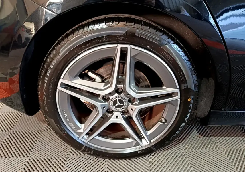 Gros plan sur la roue avant droite noire d'une Mercedes Classe A 200 AMG Line avec jante étoile AMG grise.