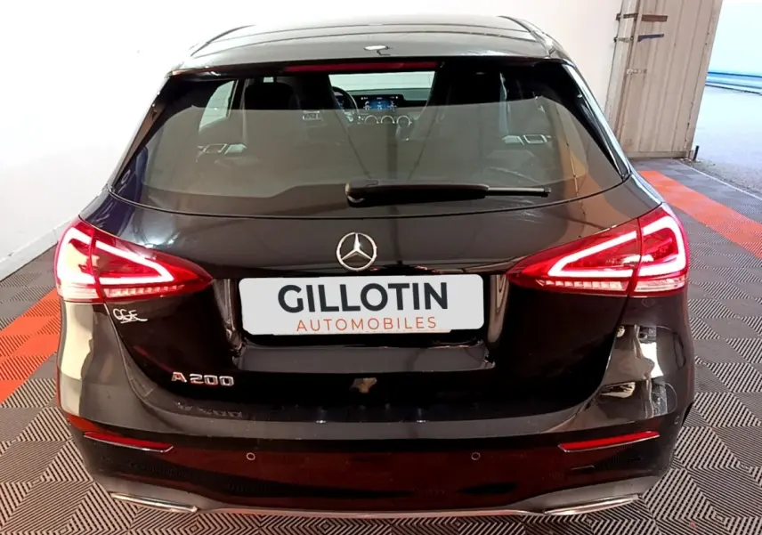 Vue arrière d'une Mercedes Classe A 200 AMG Line noire avec feux LED allumés dans un garage.