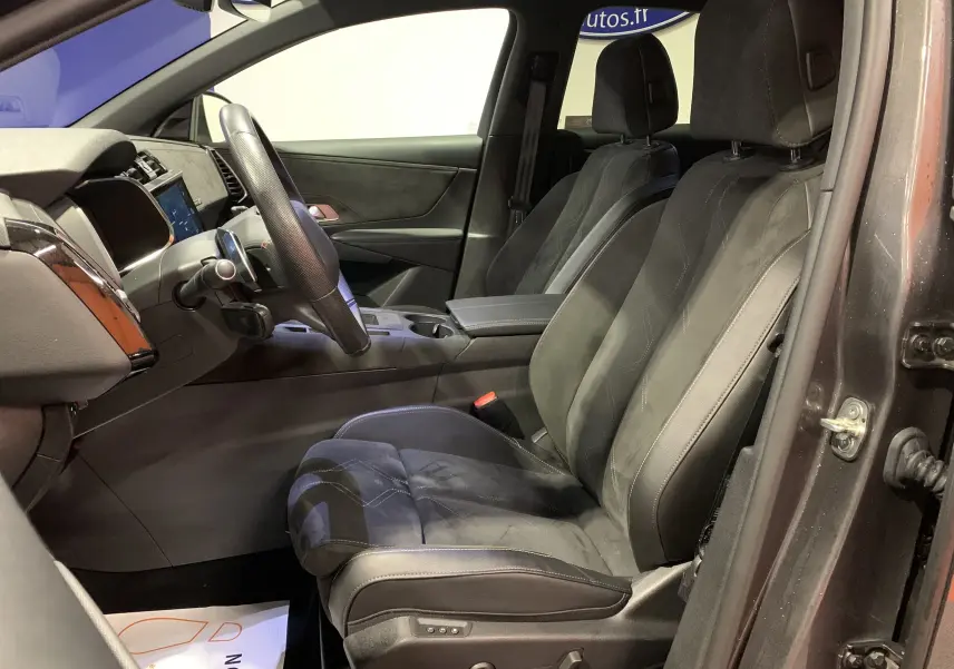 Intérieur côté conducteur du DS7 Crossback 2022 gris Platinium, sièges en cuir noir avec console centrale et volant visible.