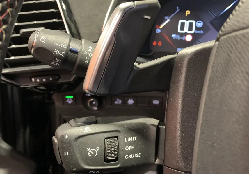 Gros plan sur les commandes au volant du DS7 Crossback 2022, soulignant les réglages du régulateur de vitesse et phares.