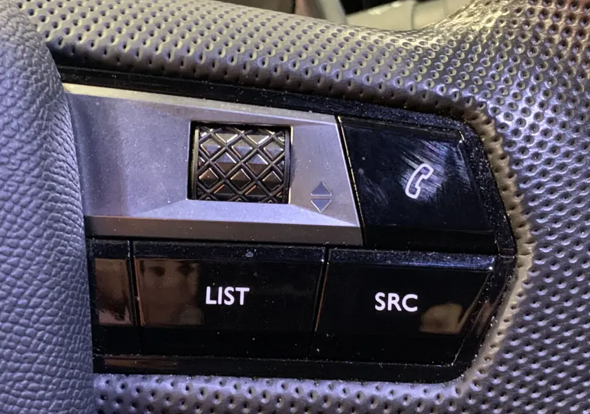 Gros plan sur les commandes du volant perforé du DS7 Crossback gris Platinium, boutons LIST et SRC visibles.