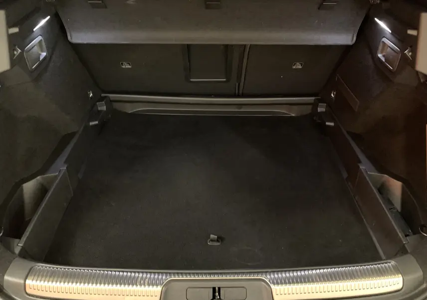 Coffre spacieux du DS7 Crossback gris Platinium vu de l'arrière, avec tapis noir et finitions métalliques sur le seuil.