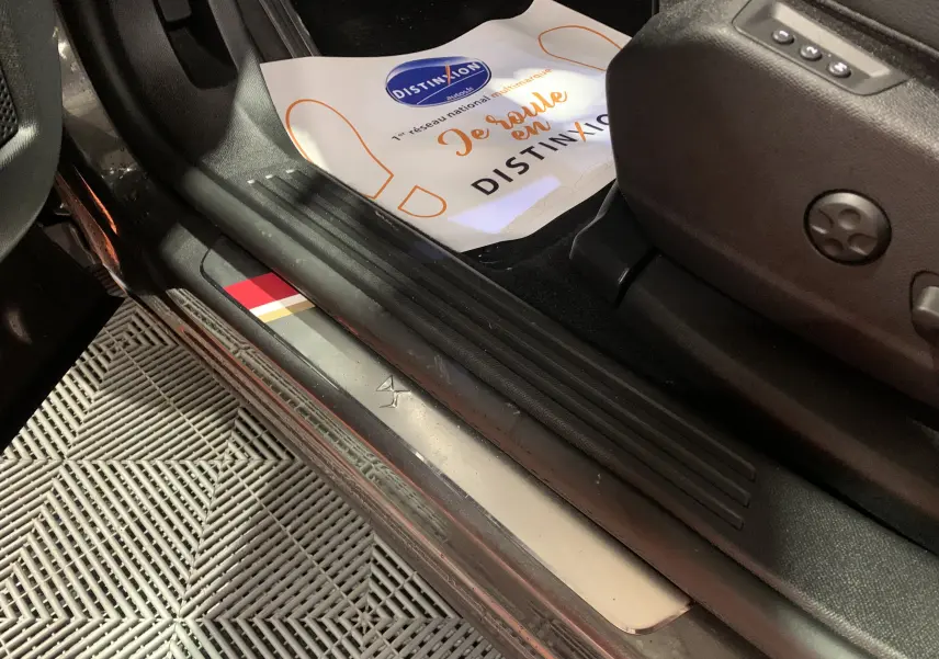 Gros plan sur la plaque de seuil côté gauche du DS7 Crossback gris Platinium avec logo DS embossé.