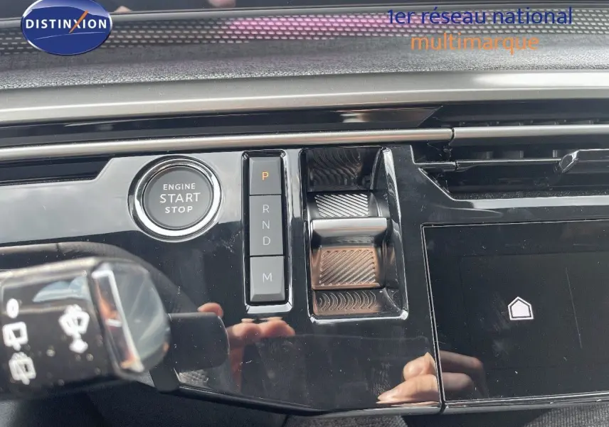 Gros plan sur la console centrale noire brillante du Peugeot 5008 Hybrid 136ch GT avec démarrage sans clé et commandes de boîte auto.