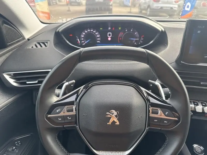 Volant cuir multifonction noir de Peugeot 3008 2022, avec tableau de bord numérique et écran tactile visible en arrière-plan.