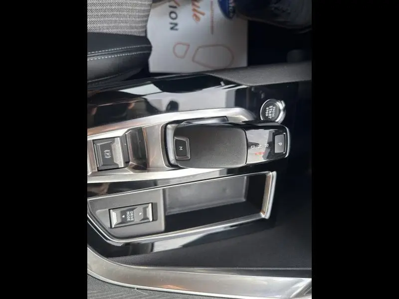 Gros plan sur la console centrale noire brillante du Peugeot 3008 2022, avec levier de vitesse automatique et commandes intégrées.
