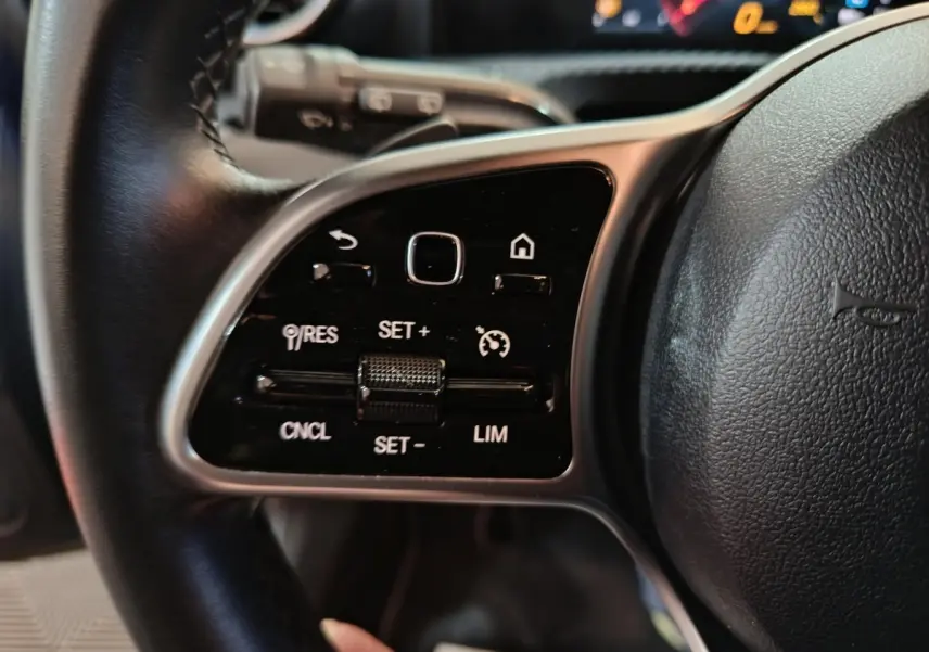 Gros plan sur le côté gauche du volant cuir de la Mercedes Classe A 250 e Business Line 2021 avec commandes intégrées.