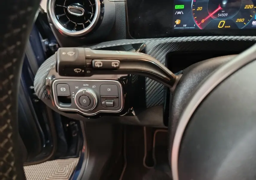 Vue rapprochée du tableau de bord côté gauche d’une Mercedes Classe A bleu, avec commandes d’éclairage et volant partiel.