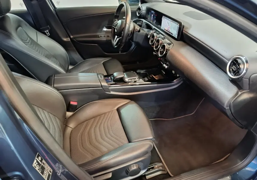 Vue intérieure côté conducteur de la Mercedes Classe A 250 e Business Line 2021 bleu, avec sièges cuir et écran tactile.