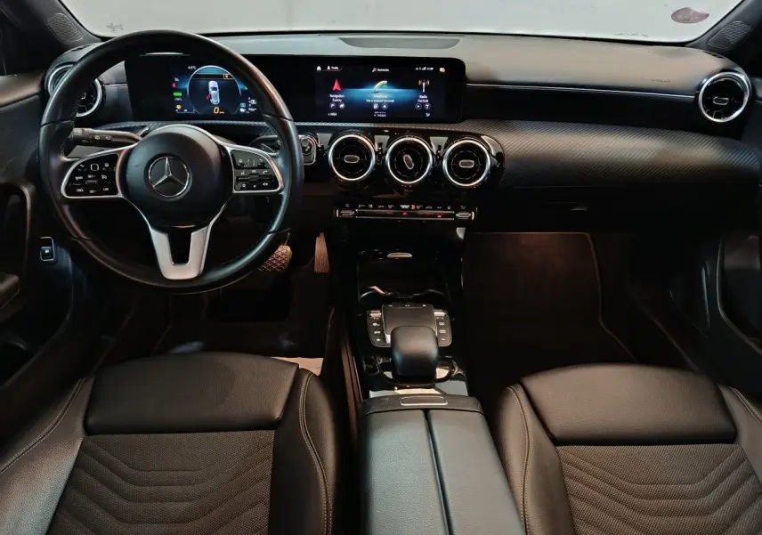 Vue intérieure avant de la Mercedes Classe A 250 e Business Line 2021 avec tableau de bord numérique et volant cuir multifonctions.