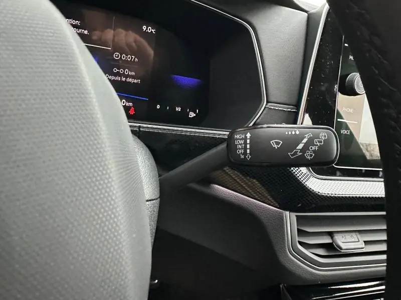 Gros plan sur la commande d’essuie-glace à gauche du volant dans l’habitacle noir du Volkswagen T-Cross jaune 2026.