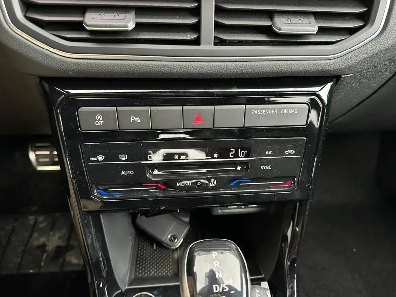 Vue rapprochée de la console centrale du Volkswagen T-Cross 2026 avec commandes climatisation et levier de boîte auto.