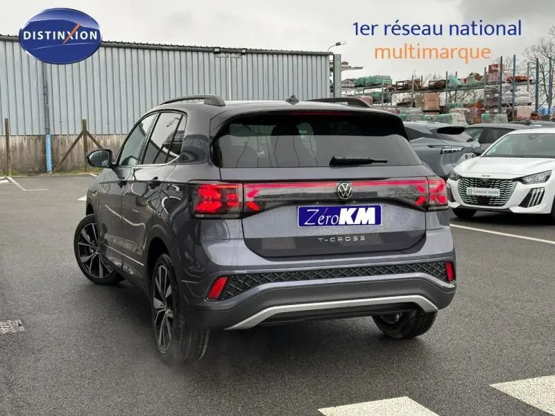 Vue 3/4 arrière d'un Volkswagen T-Cross gris métallisé avec feux arrière LED et jantes alliage, stationné en extérieur.