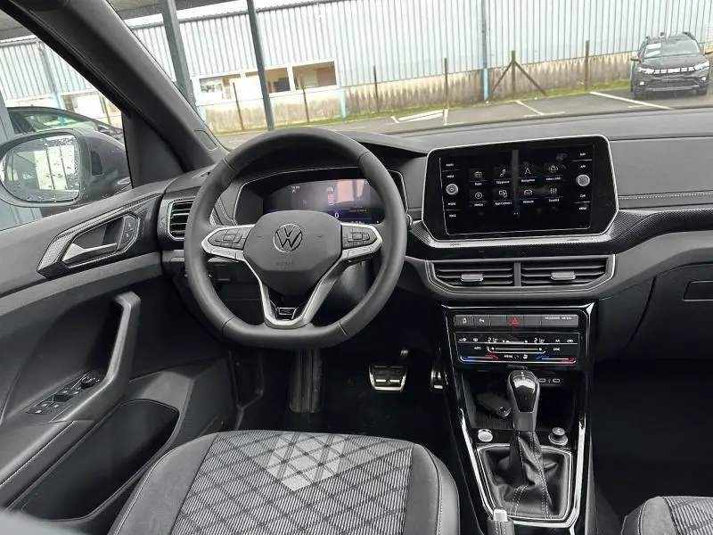 Vue intérieure avant du Volkswagen T-Cross avec volant cuir multifonction, écran tactile et sellerie R-Line gris/noir.