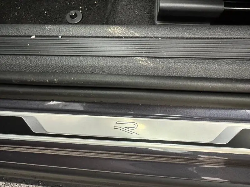 Gros plan sur la plaque de seuil de porte avec logo R du Volkswagen T-Cross 1.0 TSI 116ch R-Line, intérieur noir.