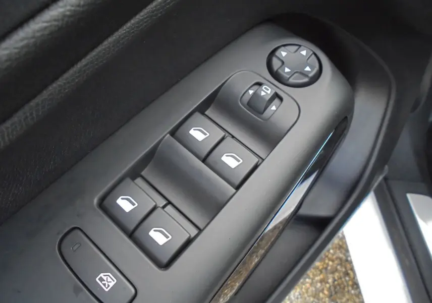 Gros plan sur les commandes de lève-vitres et rétroviseurs côté conducteur du Citroën C5 Aircross blanc banquise.