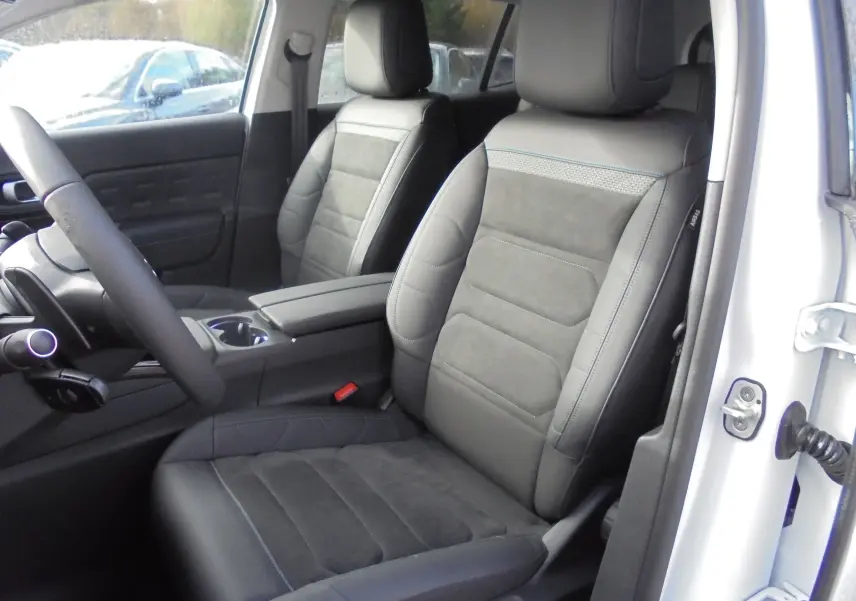 Vue intérieure côté conducteur du Citroën C5 Aircross 2022, sièges cuir noir avec surpiqûres bleues, portière blanche ouverte.