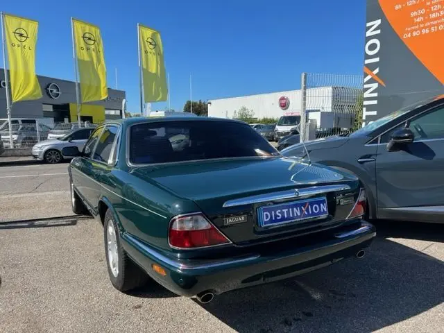Vue 3/4 arrière droite d'une Jaguar Sovereign 3.2 V8 verte de 2002, avec plaque Distinxion visible sur un parking.