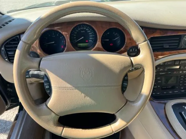 Vue intérieure du tableau de bord et volant beige d'une Jaguar Sovereign 3.2 V8 de 2002 avec finitions boisées.