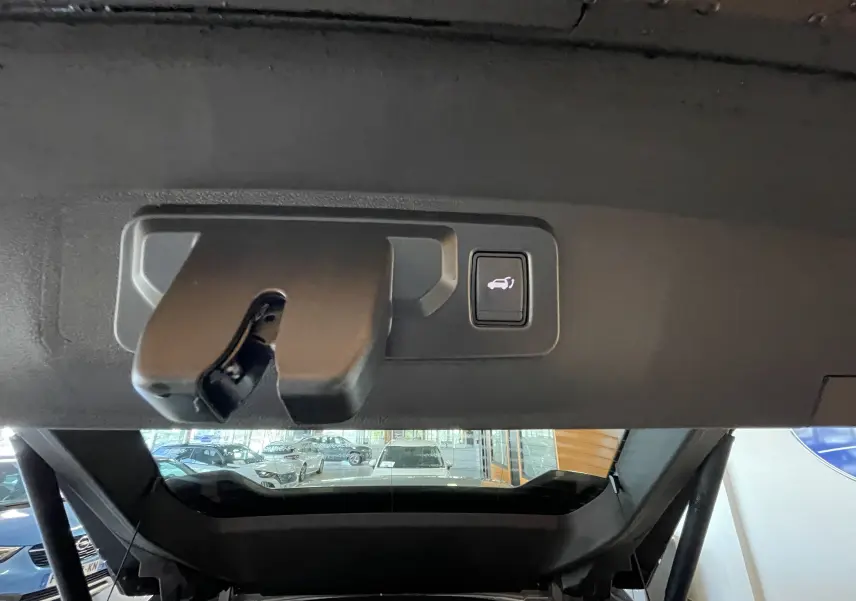 Gros plan sur la serrure et le bouton d'ouverture électrique du coffre du Renault Rafale gris shiste, vue intérieure arrière.