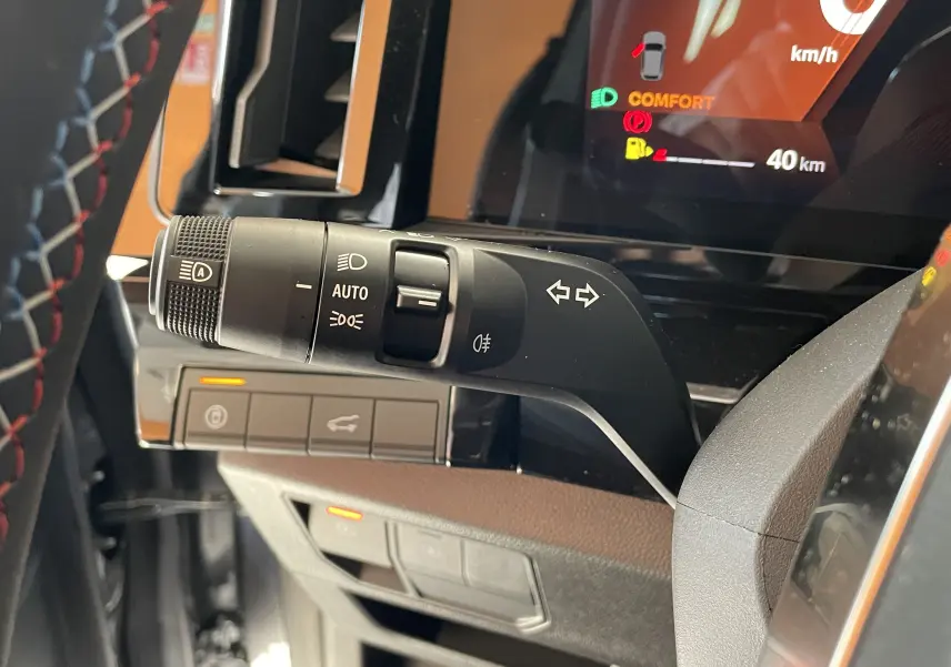 Gros plan sur la commande des feux et clignotants à gauche du volant dans le tableau de bord du Renault Rafale gris shiste 2024.