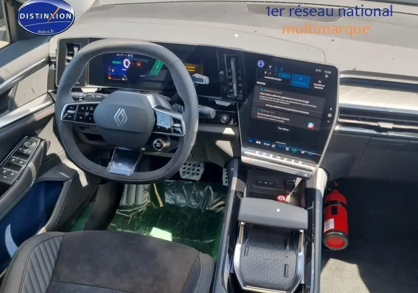 Vue intérieure avant du tableau de bord et volant Renault Rafale bleu sommet avec écran tactile vertical et accoudoir central.