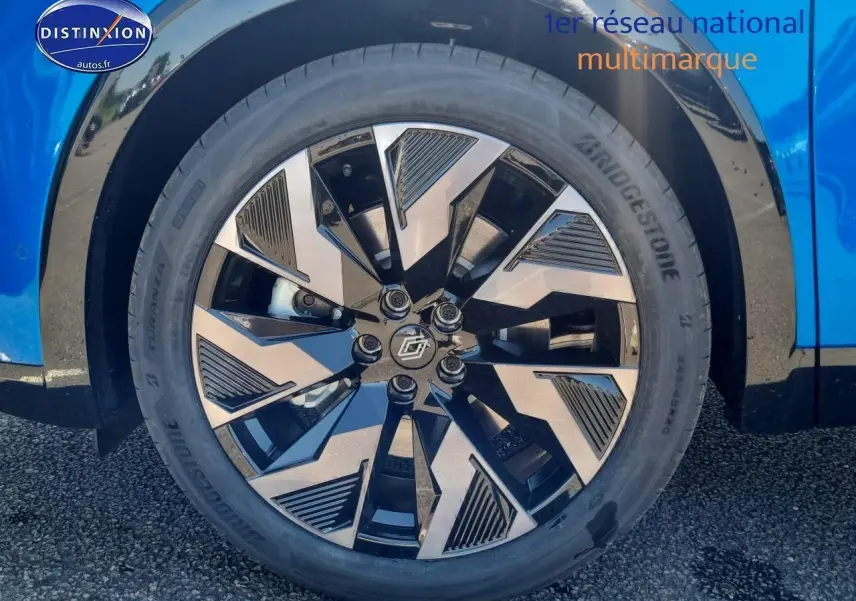 Gros plan sur la jante alu noire et argent du côté avant droit d'une Renault Rafale bleu sommet.