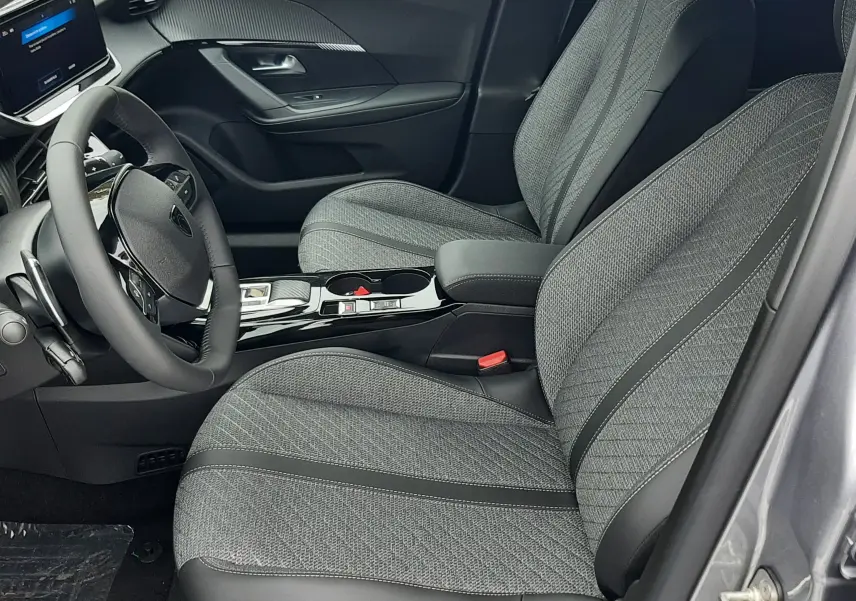 Intérieur côté conducteur du Peugeot 2008 gris Artense 2025, sièges tissu gris et tableau de bord moderne avec écran tactile.