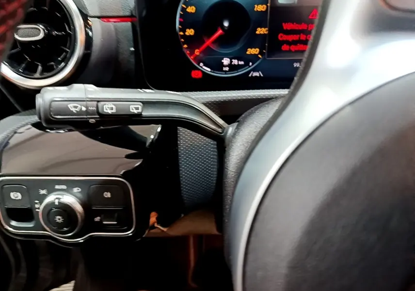 Gros plan sur le volant cuir et alu de la Mercedes Classe A 250 e AMG Line, avec tableau de bord numérique allumé.