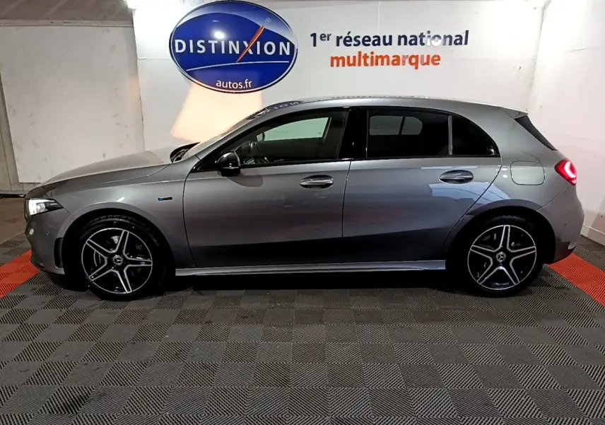 Vue de profil côté gauche d'une Mercedes Classe A 250 e AMG Line gris foncé avec jantes alliage et feux arrière allumés.