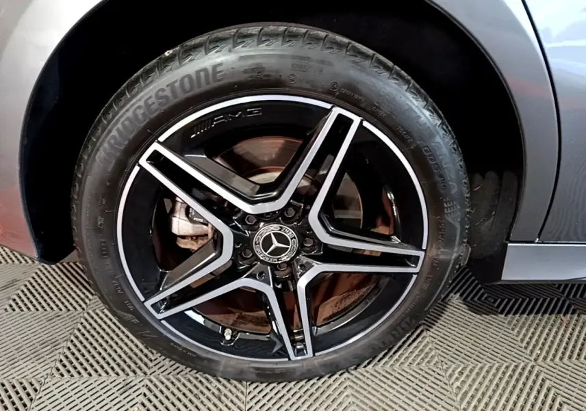 Gros plan sur la roue avant droite de la Mercedes Classe A 250 e AMG Line gris foncé avec jante AMG noire et argent.