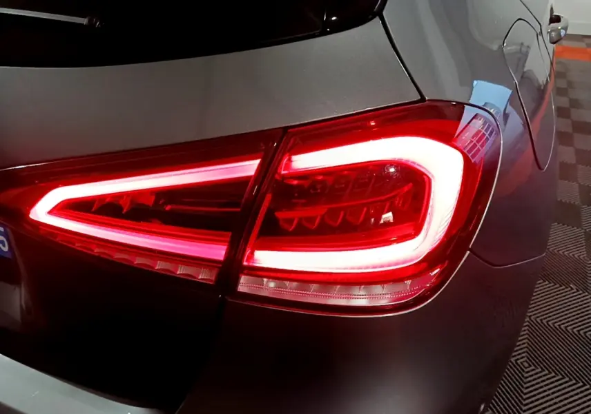 Gros plan sur le feu arrière droit allumé d'une Mercedes Classe A 250 e AMG Line gris foncé, vue arrière partielle.