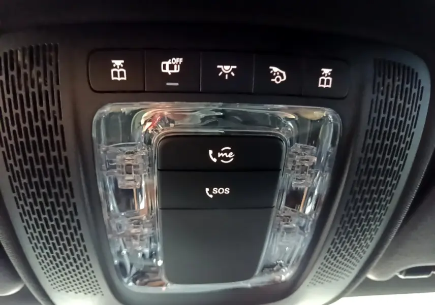 Vue en contre-plongée du panneau de commandes intérieures noires avec boutons SOS et appel d'urgence dans une Mercedes Classe A gris foncé.