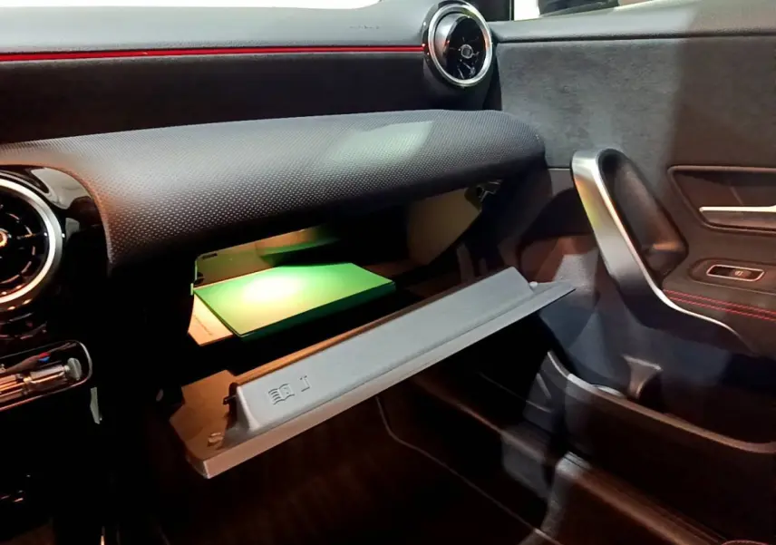 Vue intérieure côté passager du coffre à gants ouvert avec éclairage vert dans la Mercedes Classe A A 250 e AMG Line 2021.