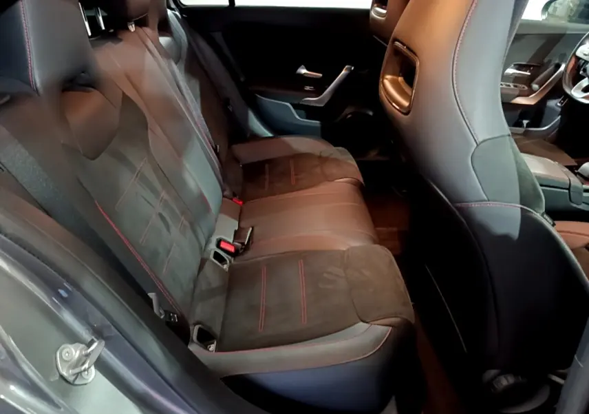 Vue intérieure côté gauche montrant la banquette arrière en cuir et alcantara noir avec surpiqûres rouges d'une Mercedes Classe A A 250 e AMG Line 2021.