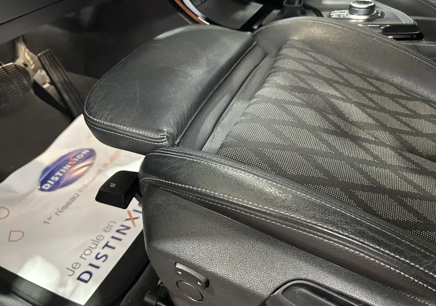 Gros plan sur le siège avant droit en cuir noir et tissu à motifs du BMW X1 blanc, version sDrive18iA 2018.
