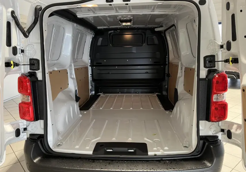 Vue arrière du Peugeot Expert Fourgon blanc 2024, portes ouvertes dévoilant l'espace de chargement vide et ses panneaux latéraux clairs.
