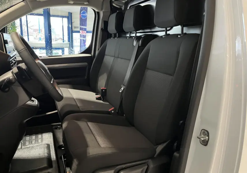Intérieur du Peugeot Expert Fourgon blanc 2024 vu côté gauche, sièges tissu bi-ton noir-gris avec volant cuir.