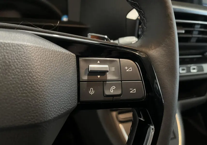 Gros plan sur les commandes à droite du volant cuir noir du Peugeot Expert Fourgon blanc 2024, avec tableau de bord moderne.