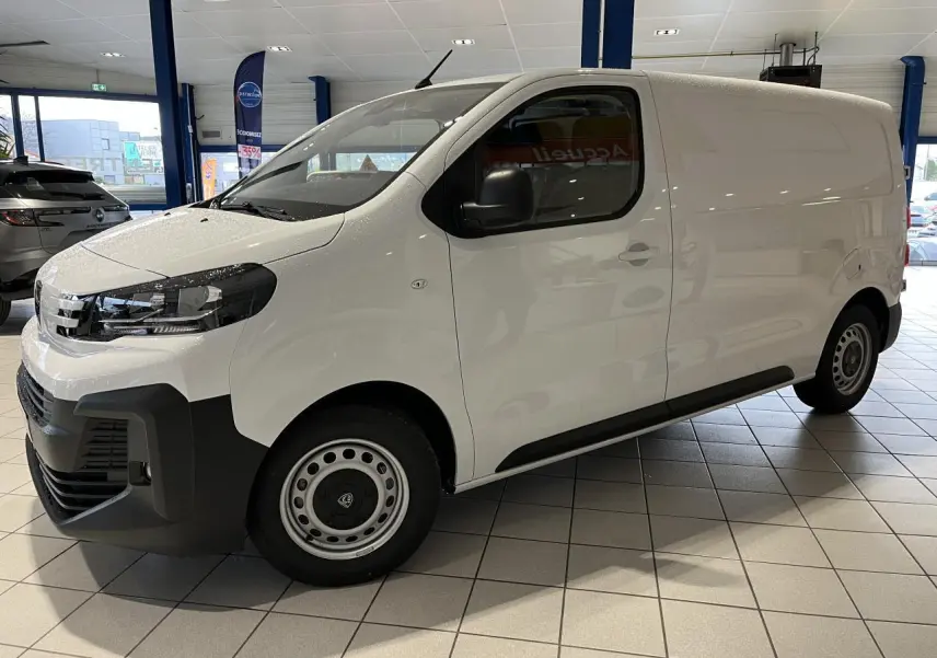 Vue de profil côté gauche d'un Peugeot Expert Fourgon blanc 2024 en showroom avec pare-chocs noirs et jantes acier.