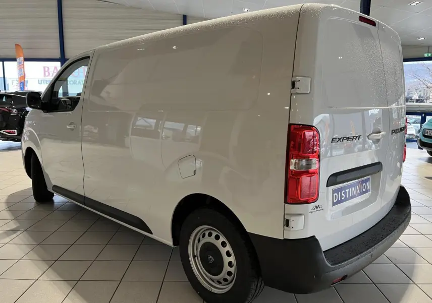 Vue 3/4 arrière droite d'un Peugeot Expert Fourgon blanc 2024 en showroom avec logo et feux arrière visibles.