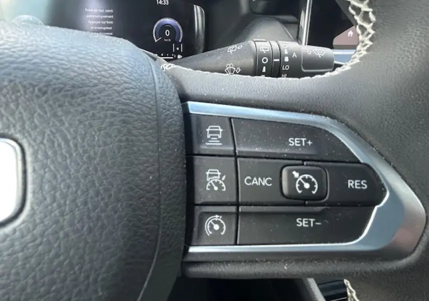 Gros plan sur les commandes du régulateur de vitesse au volant du Jeep Compass 2022, intérieur noir.