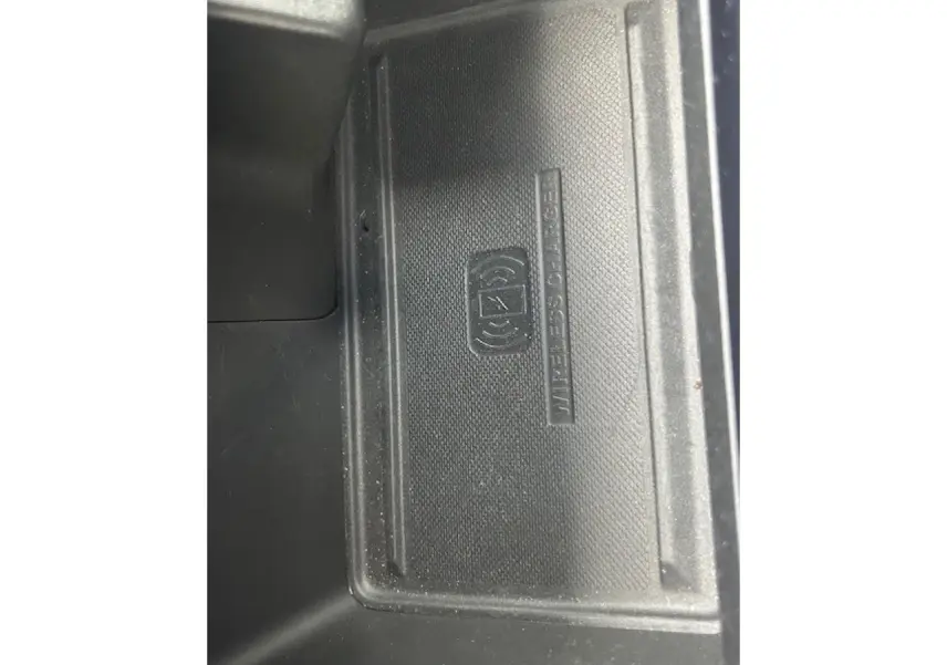 Gros plan sur le chargeur sans fil noir dans l'accoudoir central du Jeep Compass Blue Shade 2022.