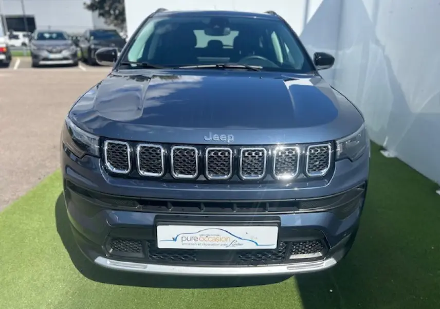 Vue frontale d'un Jeep Compass 2022 bleu métallisé avec calandre chromée et logo Jeep visible.