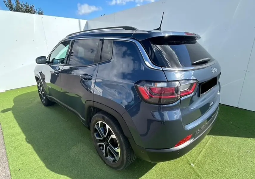 Vue 3/4 arrière droite d'un Jeep Compass bleu métallisé avec jantes alliage 18 pouces et vitres surteintées.