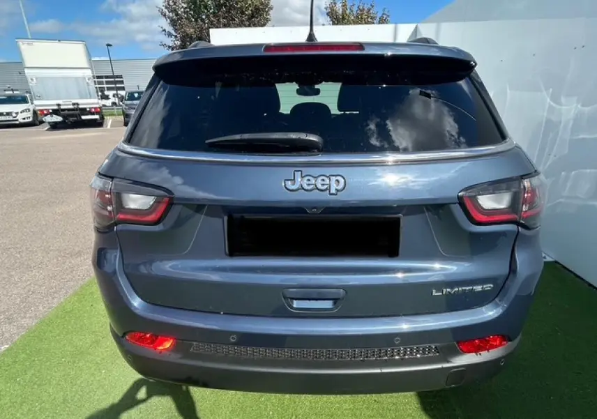 Vue arrière d'un Jeep Compass bleu métallisé avec feux LED et badge Limited visible sur un parking.